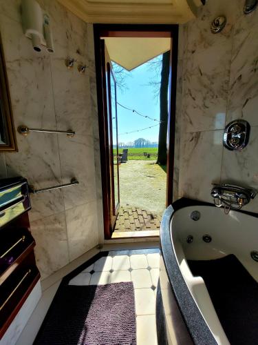 a bathroom with a bath tub and a window at Autentieke pipowagen Bijzonder Buitenaf met jacuzzi en Finse sauna in Vragender