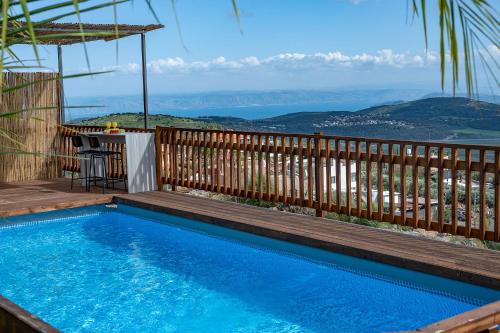 a swimming pool with a wooden fence and a view at אחוזת קסם הנוף in ‘Ein el Asad