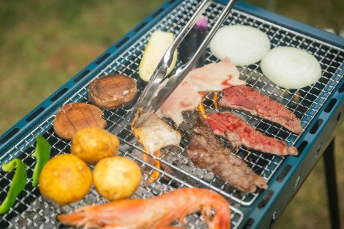 a grill with some meat and vegetables on it at ゲスト専用プライベートサウナ付き一棟貸し宿 In Utero in Kashiwazaki