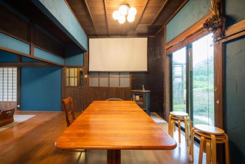 a large wooden table in a room with a large window at ゲスト専用プライベートサウナ付き一棟貸し宿 In Utero in Kashiwazaki