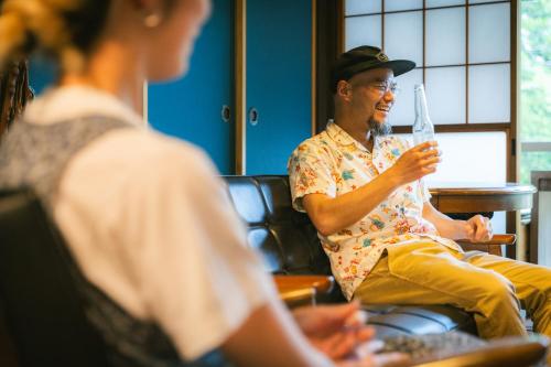 a man sitting in a chair talking to a woman at ゲスト専用プライベートサウナ付き一棟貸し宿 In Utero in Kashiwazaki