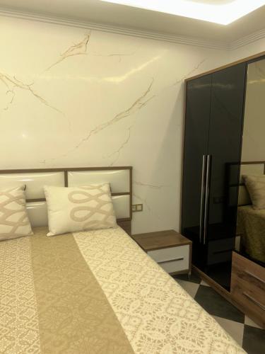 a bedroom with a bed and a marble wall at Appartement Belyouneche in Belyounech 