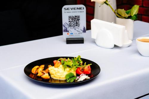 a black plate of food on a white table at Севеней Готель in Bukovel