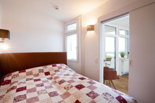 a bedroom with a bed with a quilt on it at Prinz Hamlet Wohnung Pelzi 51 in Pelzerhaken