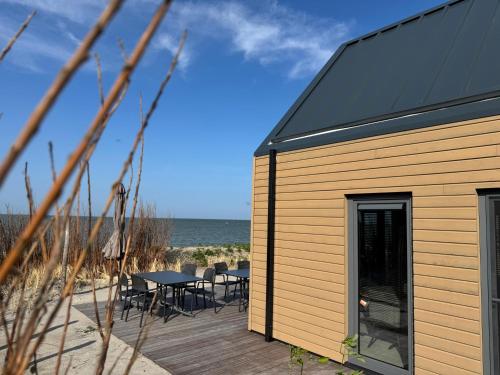 a wooden deck with tables and chairs on the beach at Enkhuizer Strand BeachHouse Sonnendeck Nr 414 in Enkhuizen