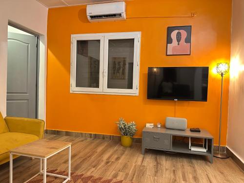 an orange living room with a couch and a tv at Maison confortable élégante et équipée pour un séjour idéal à Dakar in Dakar