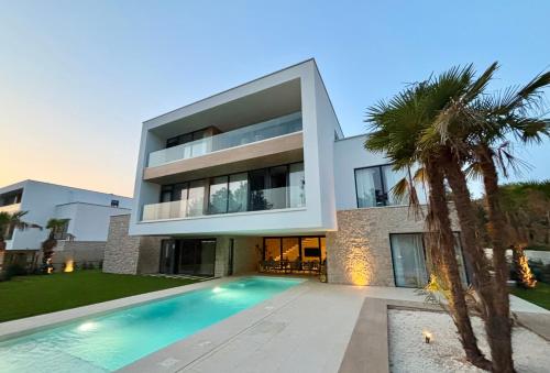 a large house with a swimming pool in front of it at Brand New Design Villa with Heated Pool and Sea view in Pomer