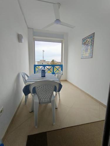 a dining room with a table and chairs and a window at appartement avec piscine in Houmt Souk