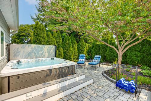 a hot tub on a patio with two blue chairs at Near Solomons Island Boardwalk Home with Hot Tub! in Solomons