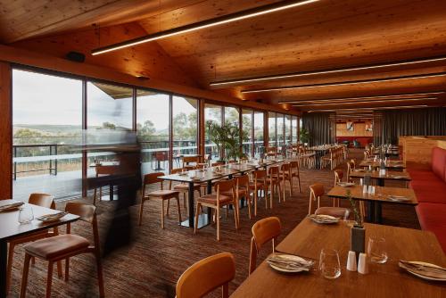 a restaurant with wooden tables and chairs and windows at Iron Creek Bay Estate in Sorell