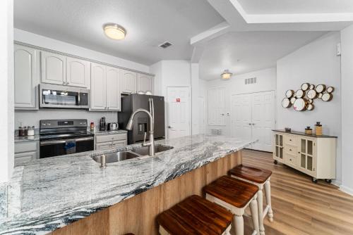 a kitchen with white cabinets and a counter with two stools at Vista Cay Resort in Orlando