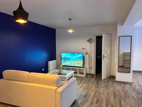 a living room with a couch and a flat screen tv at Hôtel du Parc Thionville Centre in Thionville