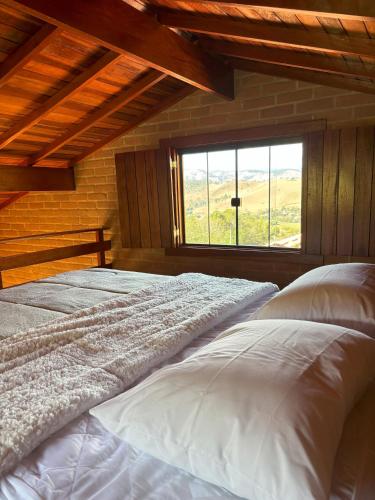 a bedroom with two beds and a large window at La Maison De Bonneval in São Bento do Sapucaí