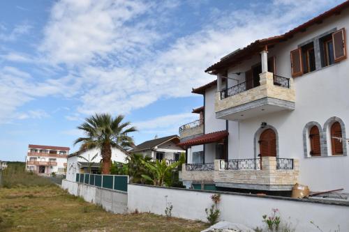 a white house with a balcony and a palm tree at Aspri Villa in Ammoudia