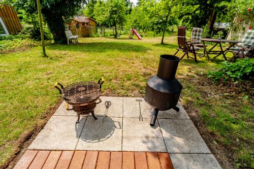 a grill and a chicken sitting on a patio at Träumen unter Bäumen - Omas lütte Obstbutze am See in Lübstorf