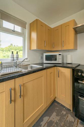 a kitchen with a sink and a microwave at Oak Cabin Overlooking Bedgebury Forest in Goudhurst