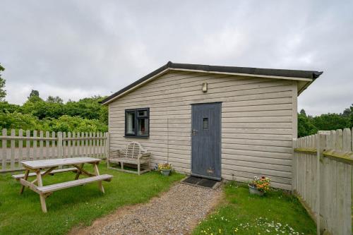 a small shed with a picnic table and a bench at Oak Cabin Overlooking Bedgebury Forest in Goudhurst