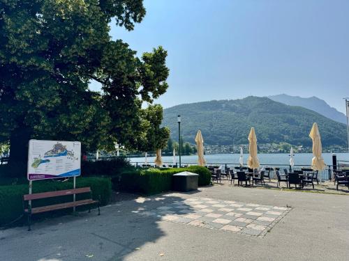a group of tables and chairs with umbrellas and the water at Apartment am Traunsee in Gmunden