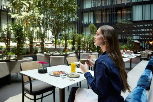 a woman sitting at a table with a plate of food at Dorothea Hotel, Budapest, Autograph Collection in Budapest