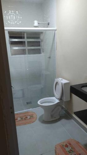a white bathroom with a toilet and a shower at Linda casa Edícula "fundos do terreno" com piscina in Itanhaém