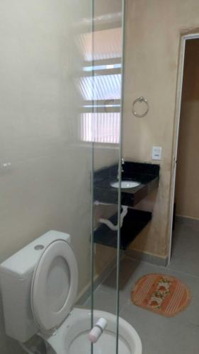 a bathroom with a white toilet and a piano at Linda casa Edícula "fundos do terreno" com piscina in Itanhaém