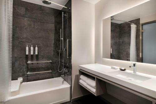 a bathroom with a sink and a tub and a shower at AC Hotel by Marriott Bentonville in Bentonville