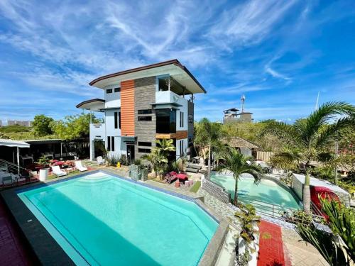 a villa with a swimming pool in front of a house at Little Rock Cebu in Mactan