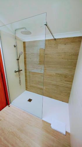 a glass shower in a room with a wooden floor at Pedra do Ouro Yoga Retreat apartment in Pataias