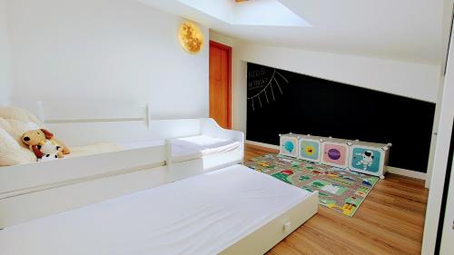 a bedroom with a white bed and a large screen at Pedra do Ouro Yoga Retreat apartment in Pataias