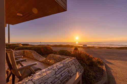 a sunset over the ocean with a bench and chairs at Little Sur Inn in Cambria