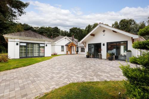 a white house with a driveway at Jaw Dropping House with Hot Tub & Heated Private Indoor Pool in Peover Superior