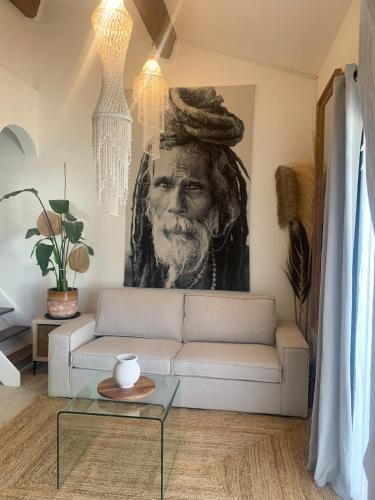 un salon avec un canapé et une peinture d'un homme dans l'établissement Les Jardins du Soleil, à Vic-la-Gardiole