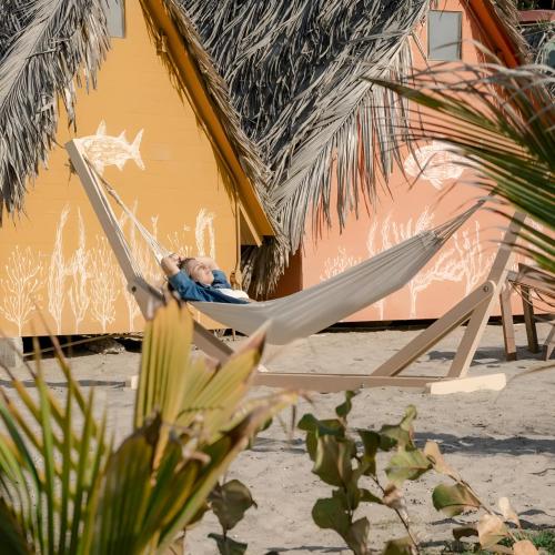 a man sleeping in a hammock on a beach at qema Mancora in Máncora