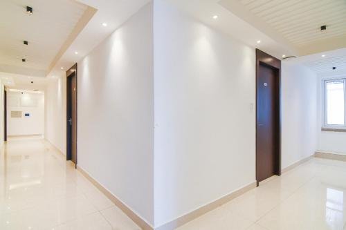 an empty hallway with white walls and white tile floors at Super Hotel O Eminent Hotel in Kolkata
