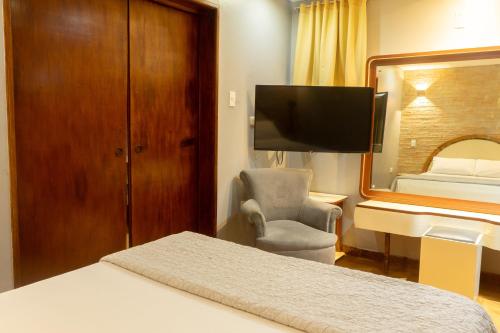 a hotel room with a bed and a desk and a television at Hotel El Arroyo in Caracas
