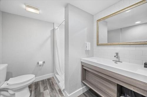 a bathroom with a toilet and a sink and a mirror at Prodigy Hotel, a Days Inn by Wyndham in Davis