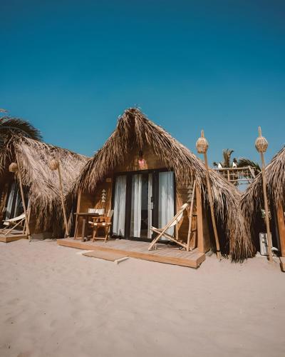 a house with a straw roof on the beach at qema Mancora in Máncora