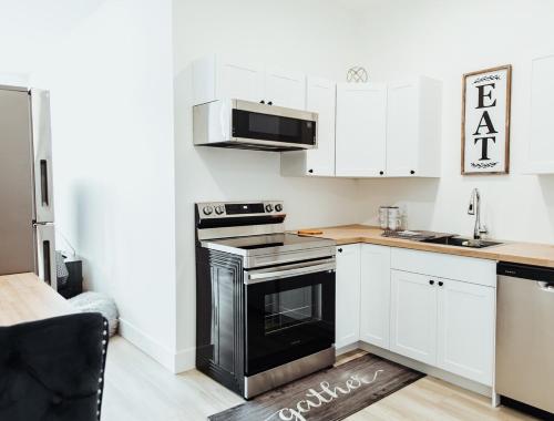 a kitchen with white cabinets and a black oven at Sapphire Lux Queen Suite in Kamloops
