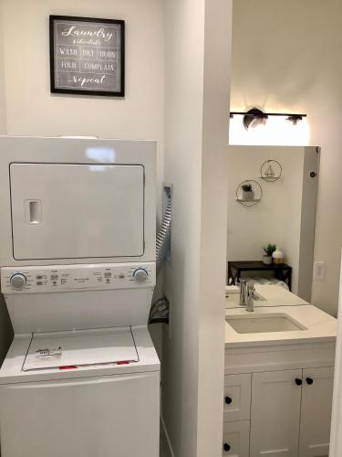 a white bathroom with a sink and a mirror at Sapphire Lux Queen Suite in Kamloops