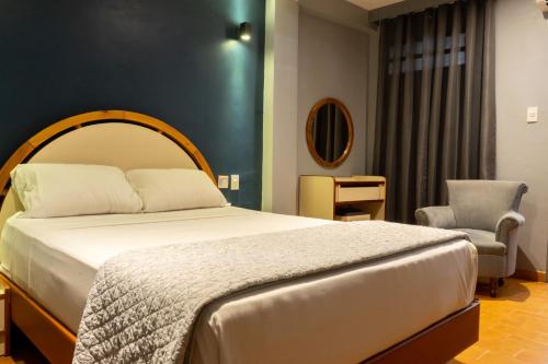 a bedroom with a large bed and a chair at Hotel El Arroyo in Caracas
