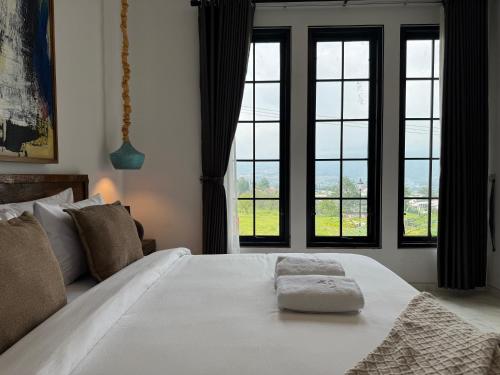 a bedroom with a large white bed with windows at Atmadeva Boutique Villas in Batu