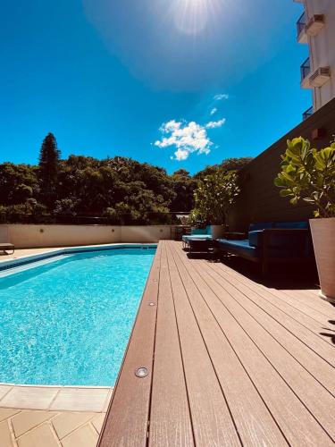 a swimming pool with a wooden deck next to a building at Hotel luxo in Joinville