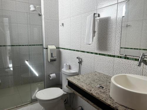 a bathroom with a toilet and a sink and a mirror at Oasis Praia Hotel in Coroa Vermelha