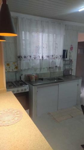 a kitchen with white cabinets and a counter top at Linda casa Edícula "fundos do terreno" com piscina in Itanhaém