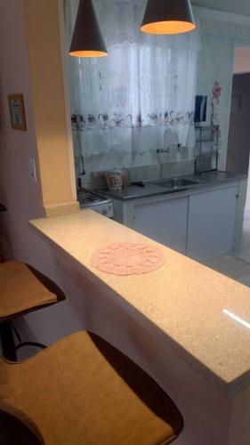 a kitchen with a counter with two lights above it at Linda casa Edícula "fundos do terreno" com piscina in Itanhaém