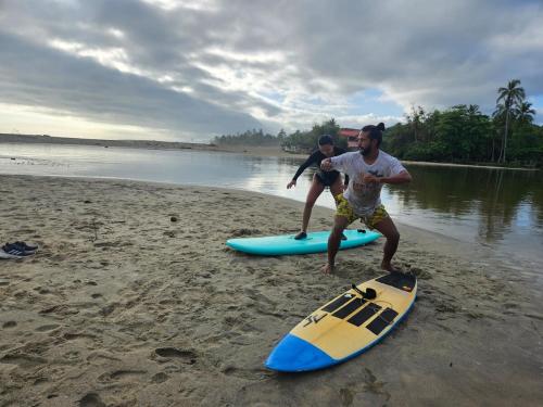 two men are standing on surfboards on a beach at Beach Suite cerca al Tayrona in Santa Marta