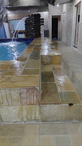 a swimming pool with a water fountain in a building at Linda casa Edícula "fundos do terreno" com piscina in Itanhaém