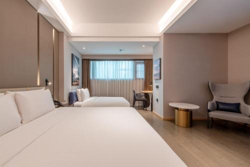 a hotel room with a large white bed and chairs at Atour Hotel Shenzhen Luohu Vientiane City in Shenzhen