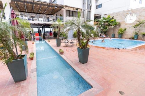 a swimming pool with palm trees in a building at Hotel Kinova - Salinas in Salinas