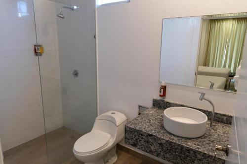 a bathroom with a toilet and a sink and a mirror at Hotel Kinova - Salinas in Salinas